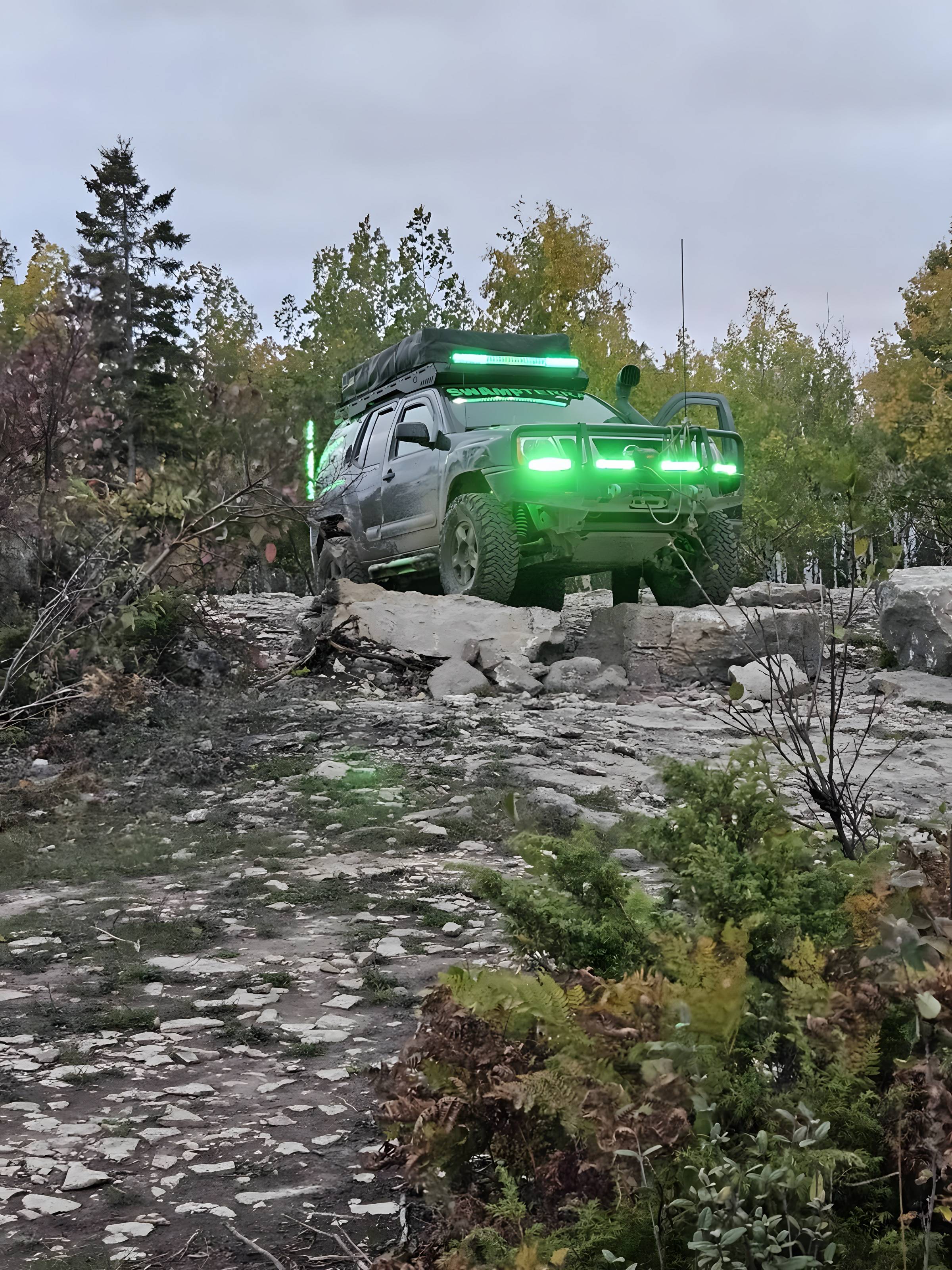Truck with green accent lights parked on a rocky clearing