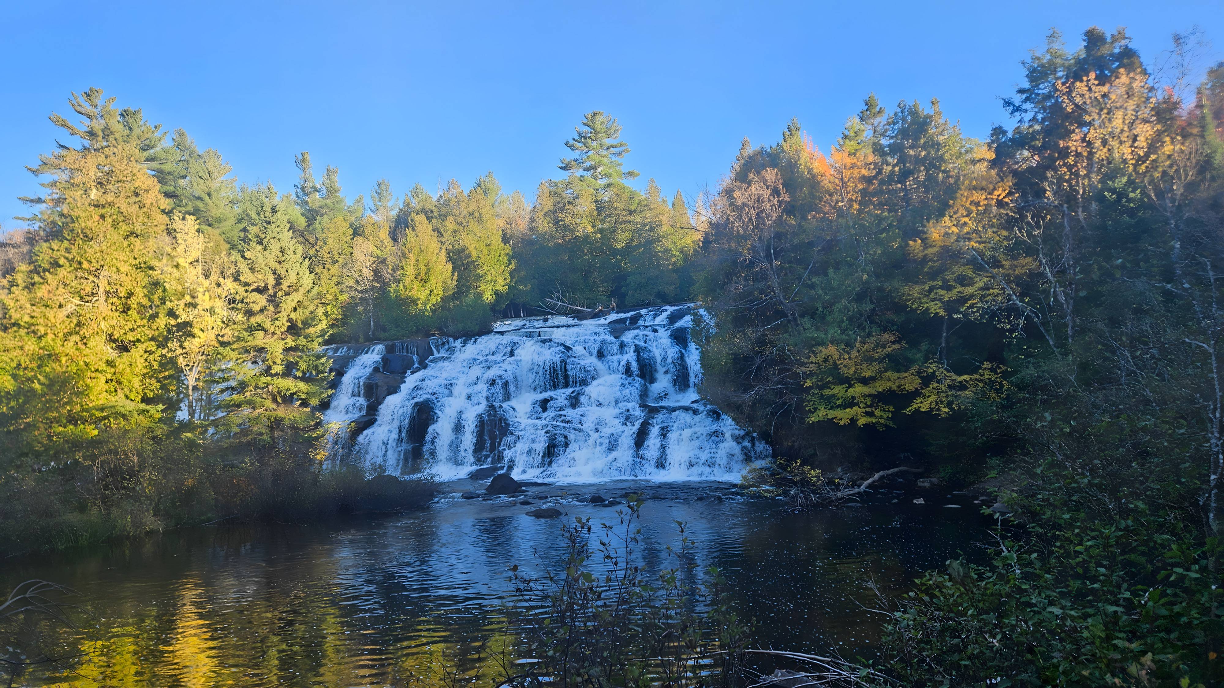 Waterfall pouring into a still pond in golden evening light